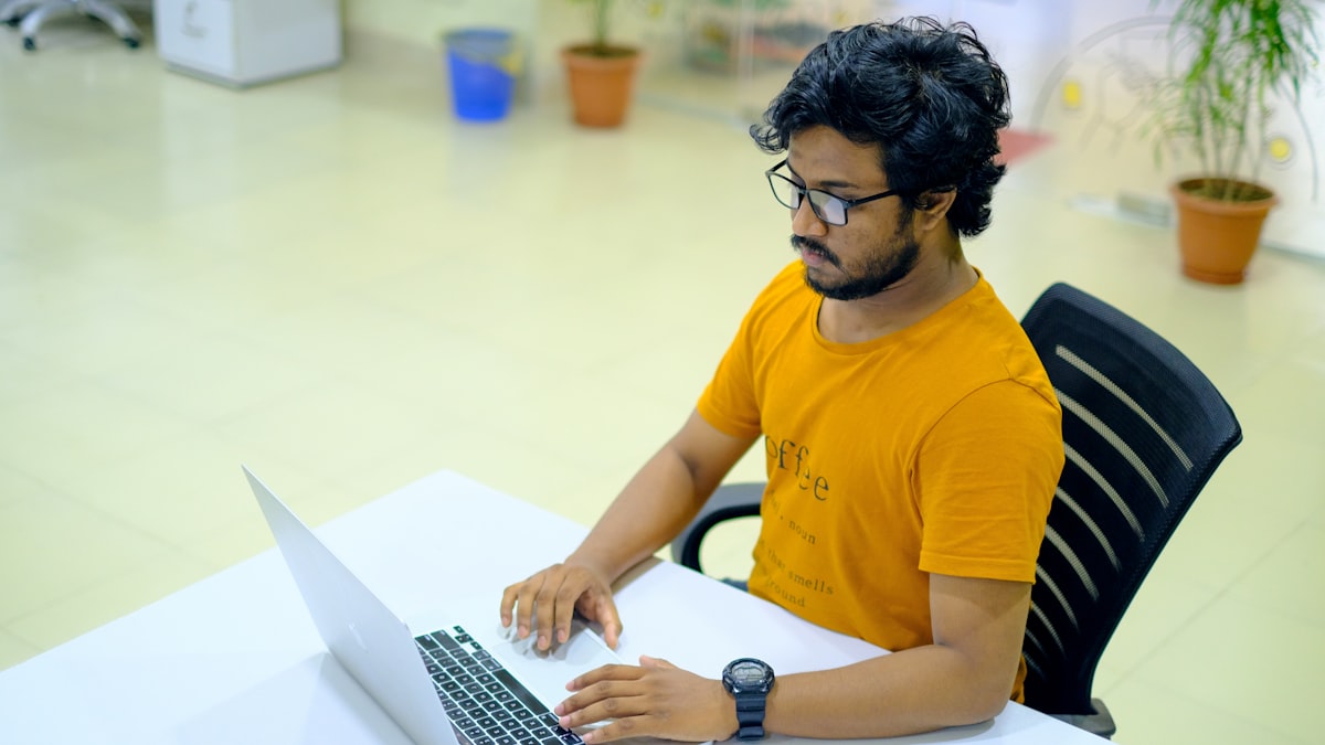 Indian young man at MacBook in office — checking Udyam registration status