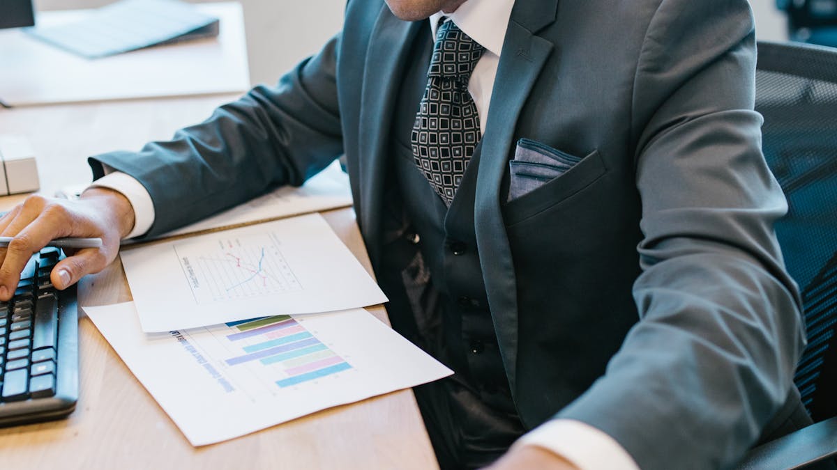 Indian businessman in suit at desk with financial reports and charts — GST review