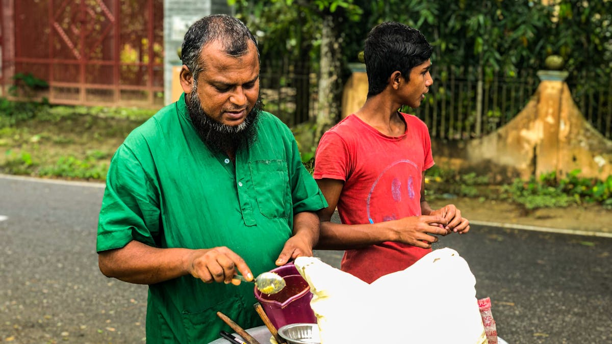 Indian father and son working together at a street food cart &mdash; family business